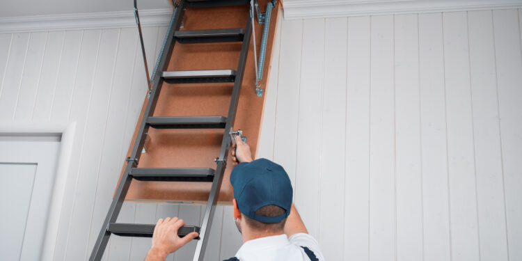 Mężczyzna otwierający schody strychowe